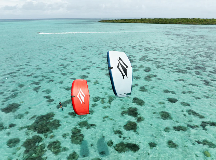 Kite foilers riding Naish Boxer kites in marginal wind conditions over flat water